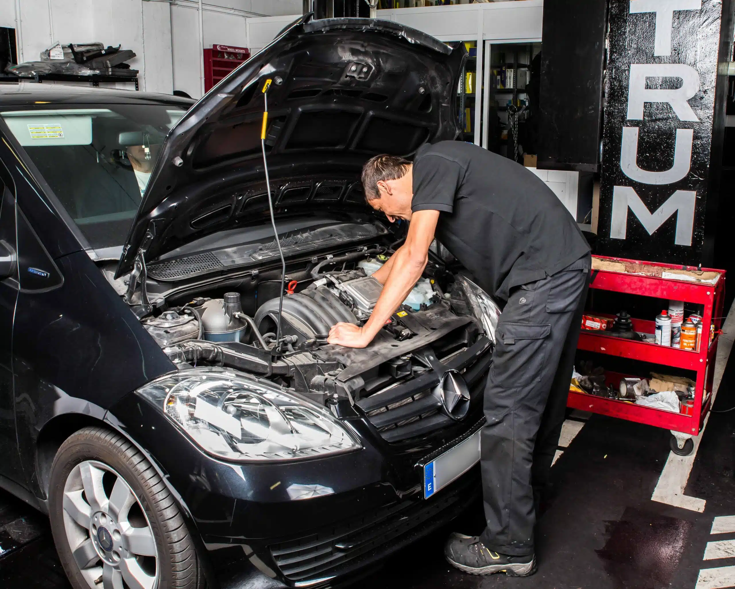 Mecánico trabajando bajo el capó de un Mercedes-Benz en Maestrum